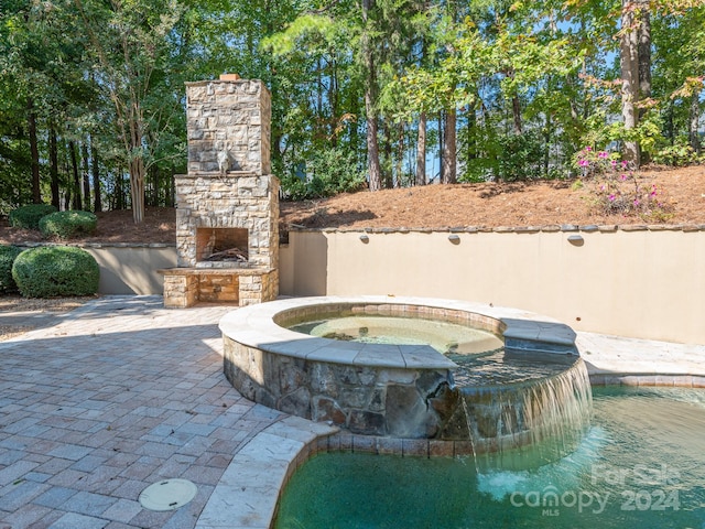 exterior space with an outdoor stone fireplace, pool water feature, and an in ground hot tub