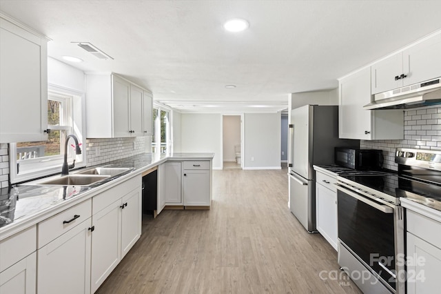 kitchen with decorative backsplash, sink, light wood-type flooring, white cabinetry, and appliances with stainless steel finishes