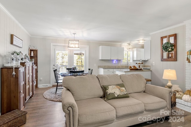 living room featuring ornamental molding, hardwood / wood-style floors, a notable chandelier, and sink