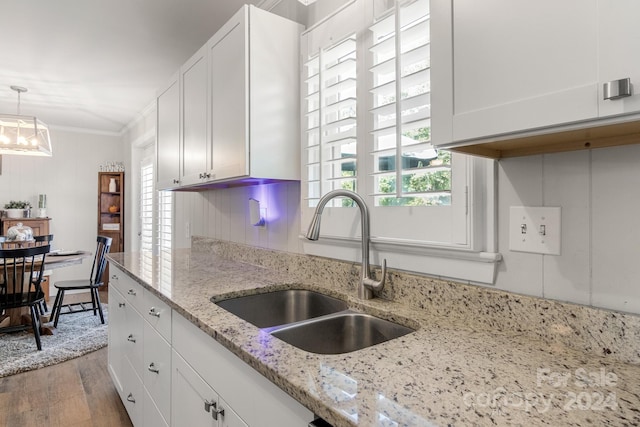 kitchen featuring white cabinetry, hardwood / wood-style flooring, pendant lighting, crown molding, and sink