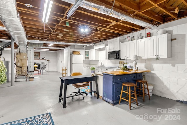 basement featuring water heater, sink, and white refrigerator