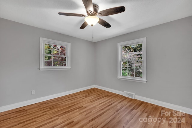 unfurnished room featuring a textured ceiling, light wood-type flooring, and ceiling fan