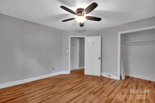 unfurnished bedroom featuring light hardwood / wood-style flooring, a textured ceiling, a closet, and ceiling fan