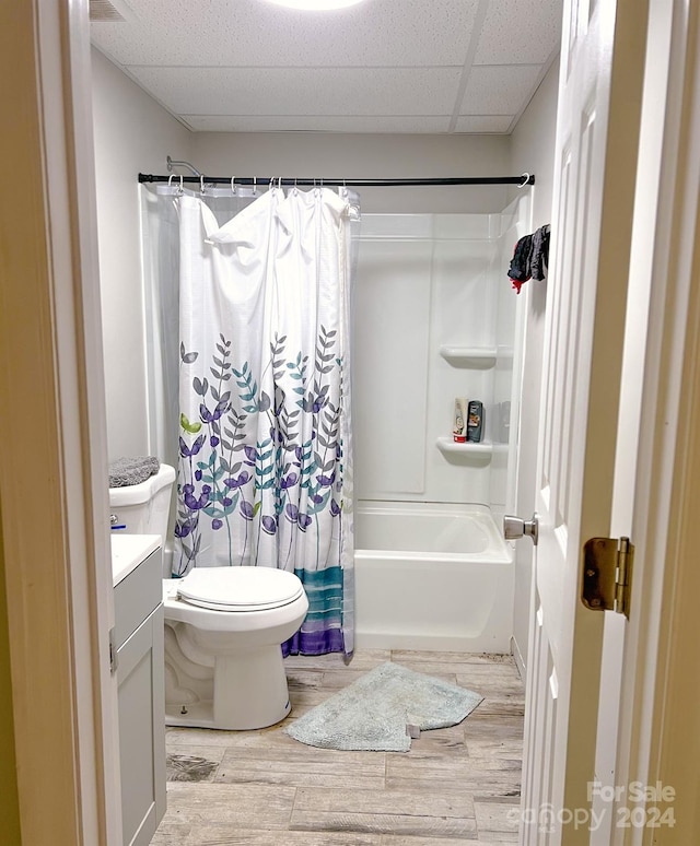 full bathroom featuring toilet, shower / bath combination with curtain, hardwood / wood-style floors, vanity, and a paneled ceiling