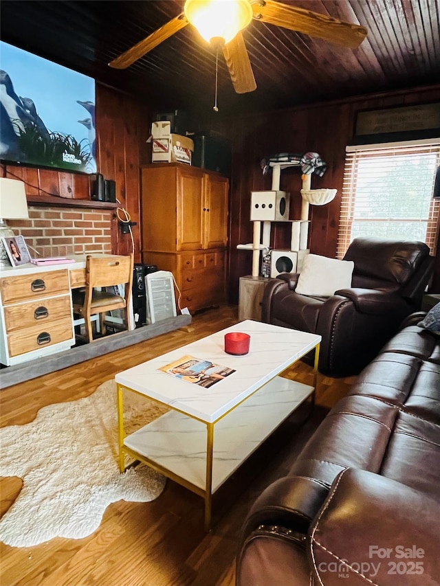 living room featuring ceiling fan, hardwood / wood-style floors, and wooden walls