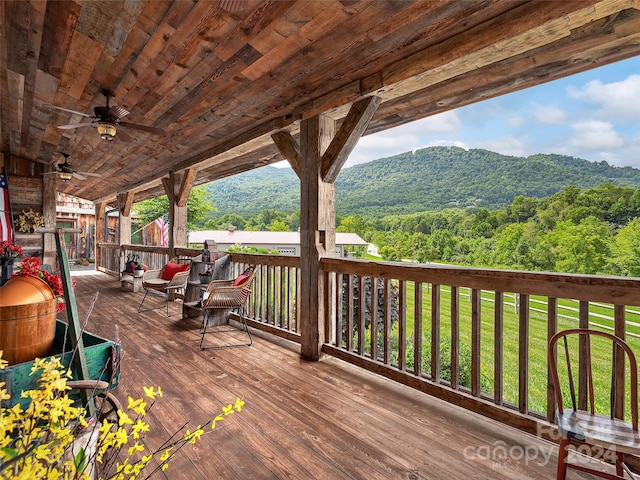 wooden terrace featuring a mountain view, a lawn, and ceiling fan