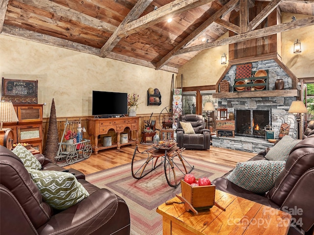 living room featuring high vaulted ceiling, wood ceiling, a stone fireplace, beam ceiling, and hardwood / wood-style flooring