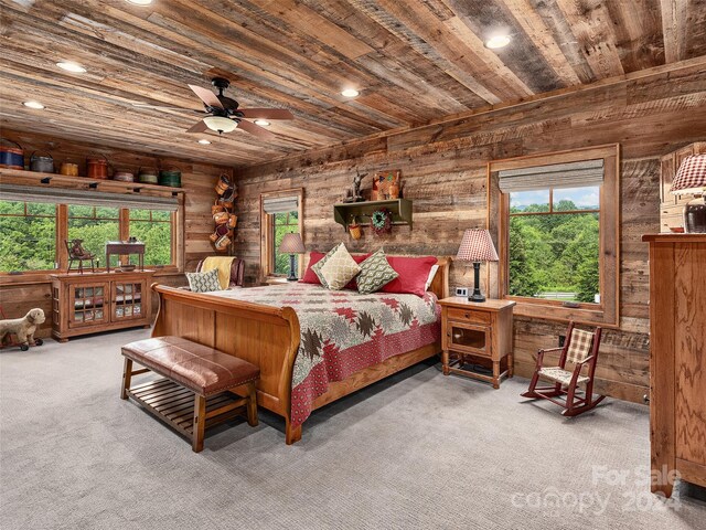 carpeted bedroom with multiple windows, wood walls, wood ceiling, and ceiling fan