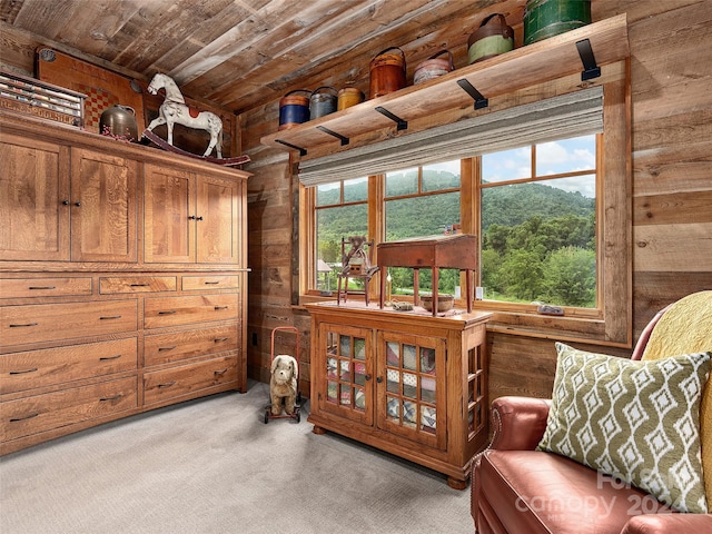 sitting room with wood ceiling, wooden walls, and light colored carpet