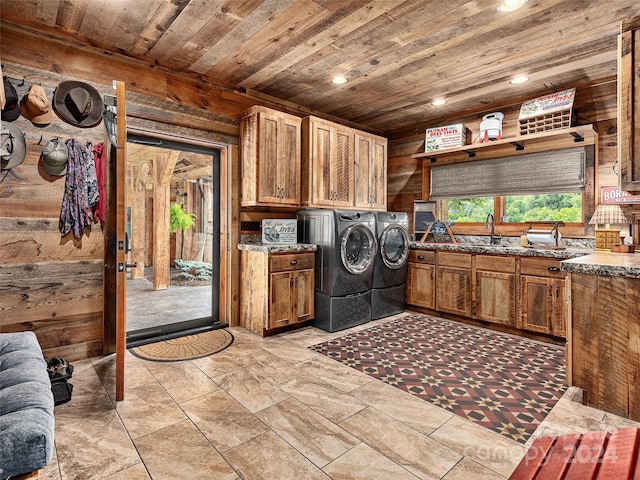 clothes washing area featuring wood walls, washing machine and dryer, sink, wood ceiling, and cabinets