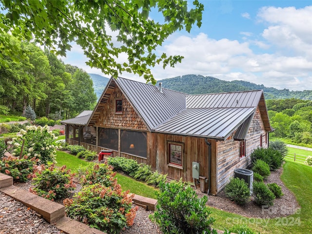 exterior space with a sunroom, a mountain view, and cooling unit