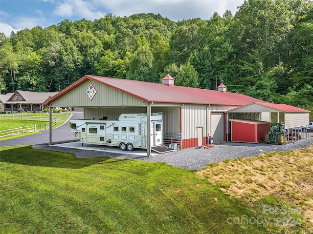 view of front of home featuring a garage, a front lawn, and an outbuilding