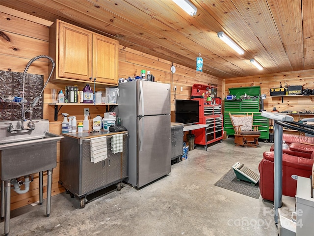 kitchen with light brown cabinetry, wooden walls, wood ceiling, and stainless steel refrigerator