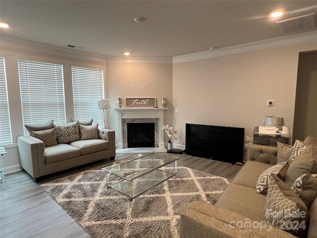 living room with wood-type flooring, ornamental molding, and a high end fireplace