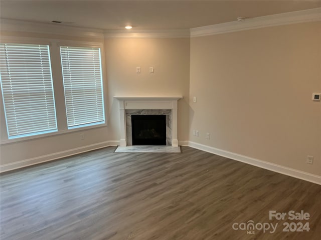 unfurnished living room with dark hardwood / wood-style floors, crown molding, and a high end fireplace