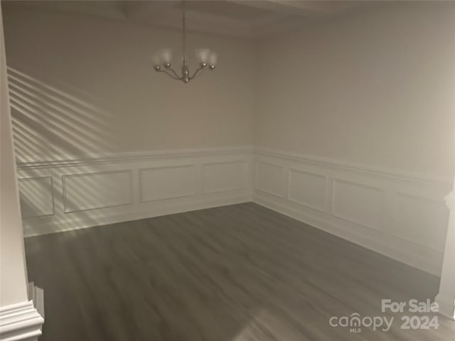 empty room with an inviting chandelier and dark hardwood / wood-style flooring