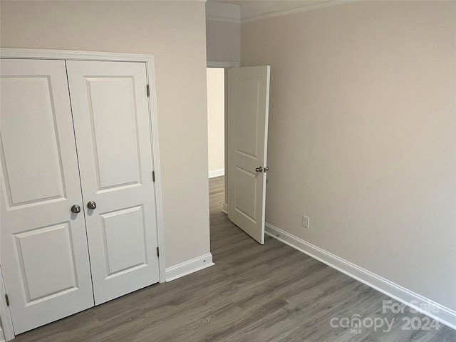 unfurnished bedroom featuring hardwood / wood-style flooring, a closet, and ornamental molding