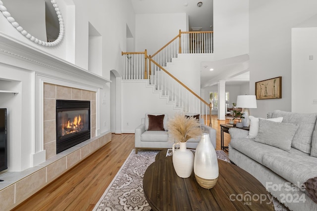 living room with light hardwood / wood-style flooring, a tiled fireplace, and a high ceiling