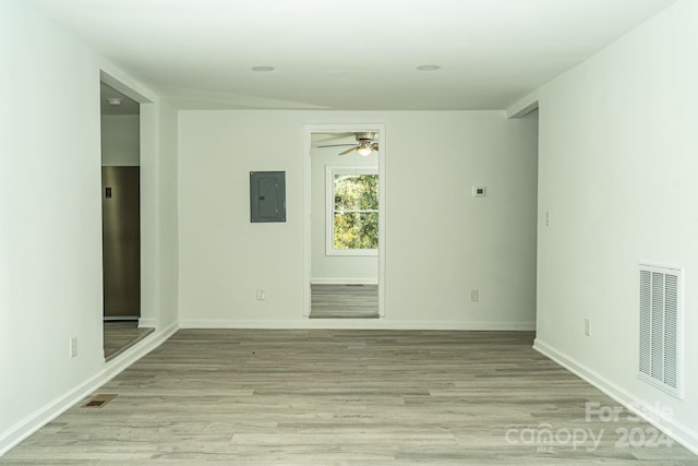 spare room with ceiling fan, electric panel, and light hardwood / wood-style flooring