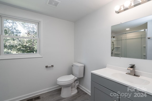 bathroom with toilet, walk in shower, vanity, and hardwood / wood-style flooring