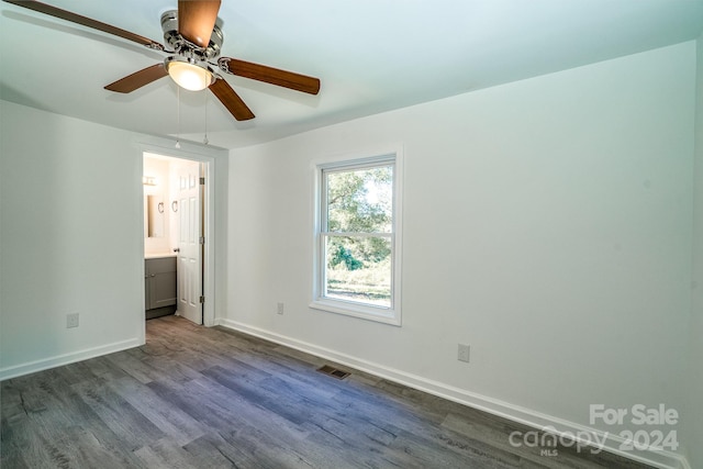 unfurnished bedroom with dark wood-type flooring, ensuite bathroom, and ceiling fan