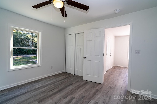 unfurnished bedroom featuring dark wood-type flooring, a closet, and ceiling fan