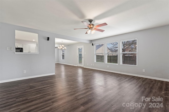 unfurnished living room featuring ceiling fan with notable chandelier and dark hardwood / wood-style flooring