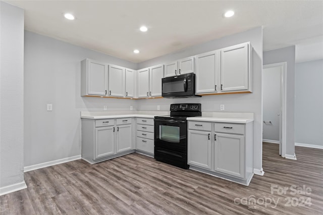 kitchen with hardwood / wood-style floors, white cabinetry, and black appliances