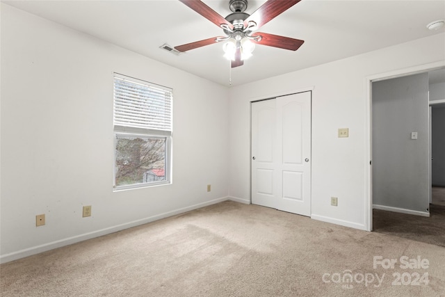 unfurnished bedroom with ceiling fan, light colored carpet, and a closet