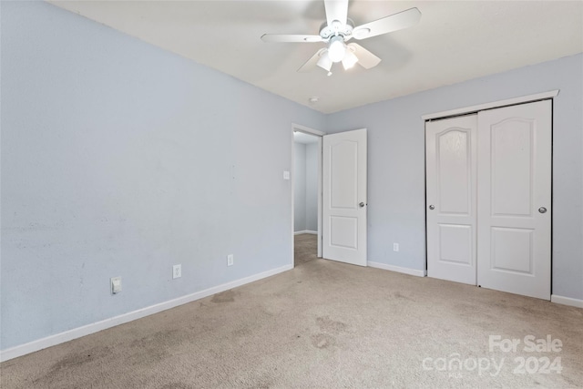 unfurnished bedroom with ceiling fan, light carpet, and a closet