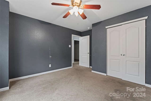 unfurnished bedroom featuring ceiling fan, light colored carpet, and a closet