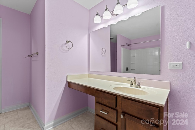 bathroom with tile patterned flooring, vanity, and a shower