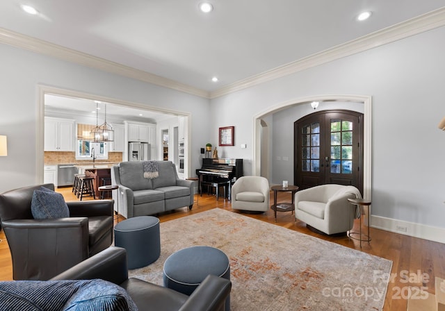 living room with wood-type flooring, ornamental molding, and french doors