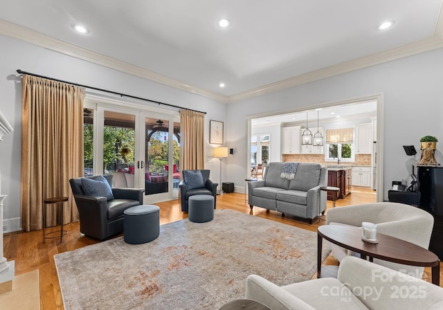 living room featuring light wood-type flooring, french doors, and ornamental molding