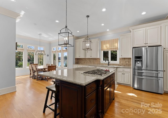 kitchen featuring stainless steel appliances, hanging light fixtures, light stone countertops, a breakfast bar, and a kitchen island