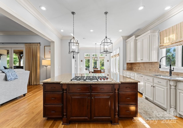 kitchen featuring hanging light fixtures, stainless steel appliances, light wood-type flooring, dark brown cabinets, and white cabinetry