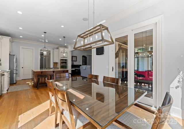 dining room with ornamental molding and light hardwood / wood-style floors