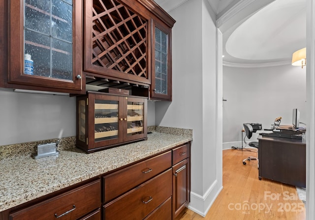 interior space featuring light hardwood / wood-style floors, crown molding, and light stone countertops