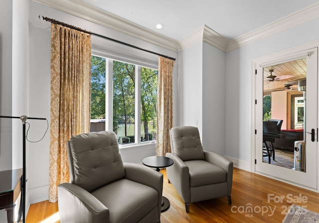 sitting room with wood-type flooring, crown molding, and a healthy amount of sunlight