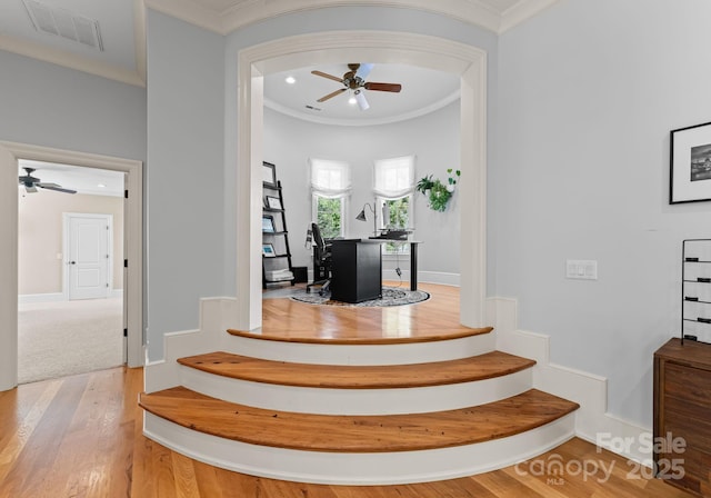 stairway featuring ceiling fan, ornamental molding, and hardwood / wood-style floors