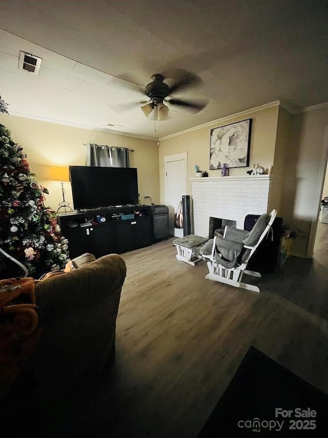 living room with ceiling fan, ornamental molding, hardwood / wood-style floors, and a brick fireplace