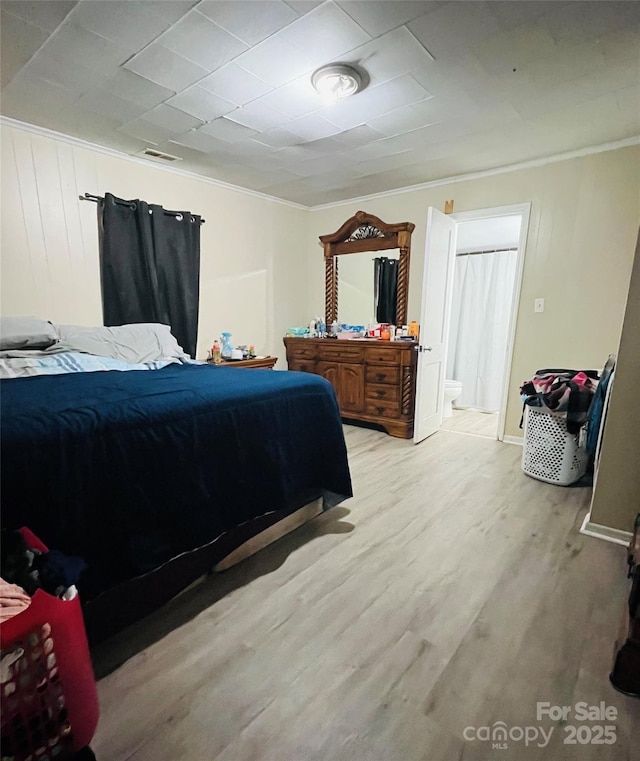 bedroom with crown molding, ensuite bathroom, and light hardwood / wood-style flooring