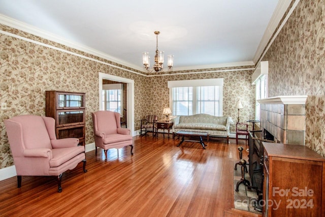 sitting room with ornamental molding, a notable chandelier, and hardwood / wood-style flooring