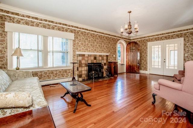 living room featuring hardwood / wood-style flooring, a chandelier, ornamental molding, a fireplace, and baseboard heating