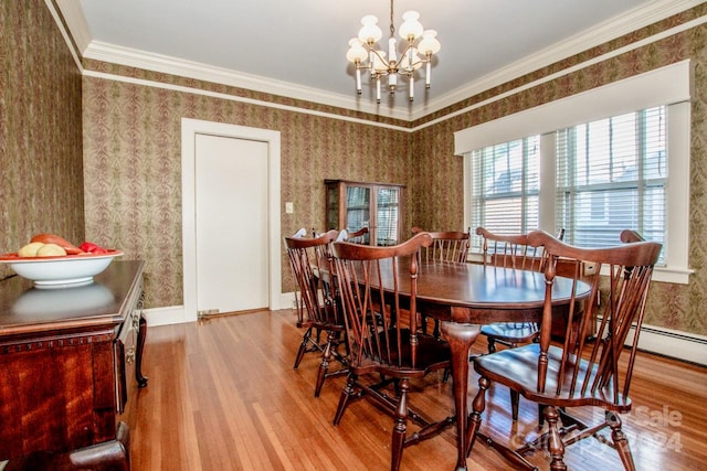 dining space with ornamental molding, hardwood / wood-style flooring, and a chandelier