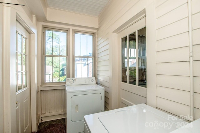 laundry room featuring wooden walls and washer and clothes dryer