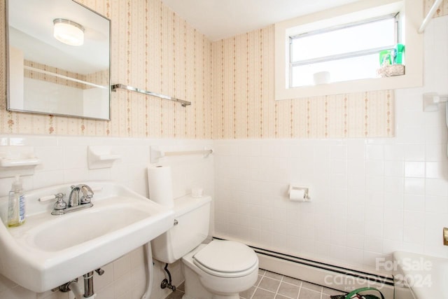 bathroom featuring a baseboard heating unit, tile walls, toilet, sink, and tile patterned floors