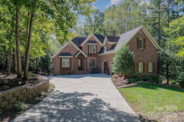 view of front of home with driveway, a front yard, and brick siding