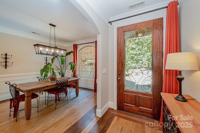 foyer featuring visible vents, arched walkways, crown molding, and wood finished floors