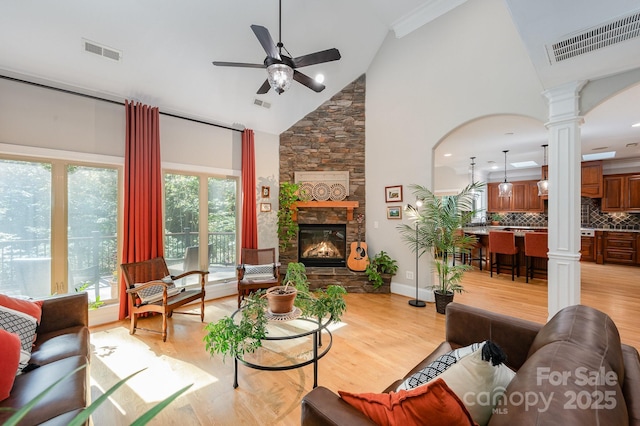 living room featuring decorative columns, visible vents, a ceiling fan, light wood-style flooring, and a fireplace